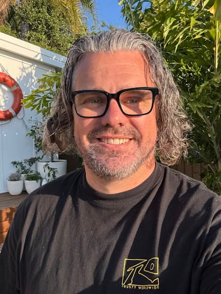 Scott, smiling outdoors in a garden